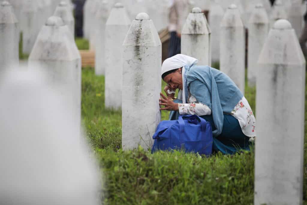 Una madre bosniaca piange sulla lapide del proprio figlio, vittima del genocidio di Srebrenica.
