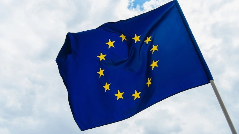 bandiera europea in primo piano, sullo sfondo cielo nuvoloso