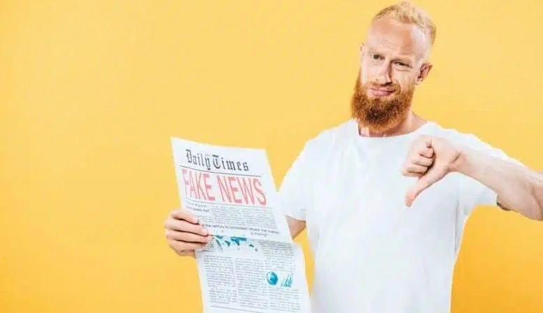 giovane con capelli e barba rossi legge un giornale il cui titolo è FAKE NEWS